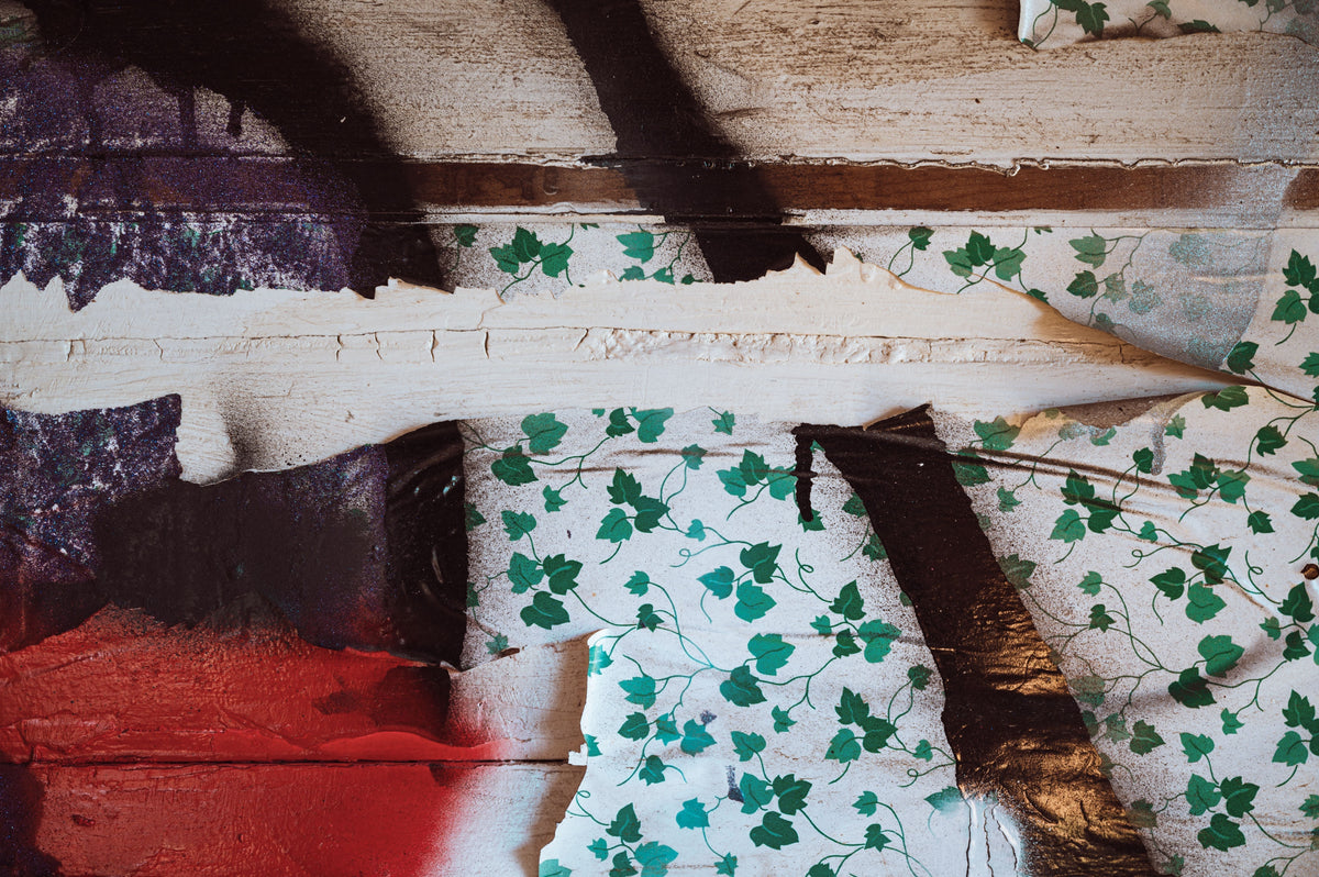 Layers of torn wallpaper revealing different colors and textures underneath.