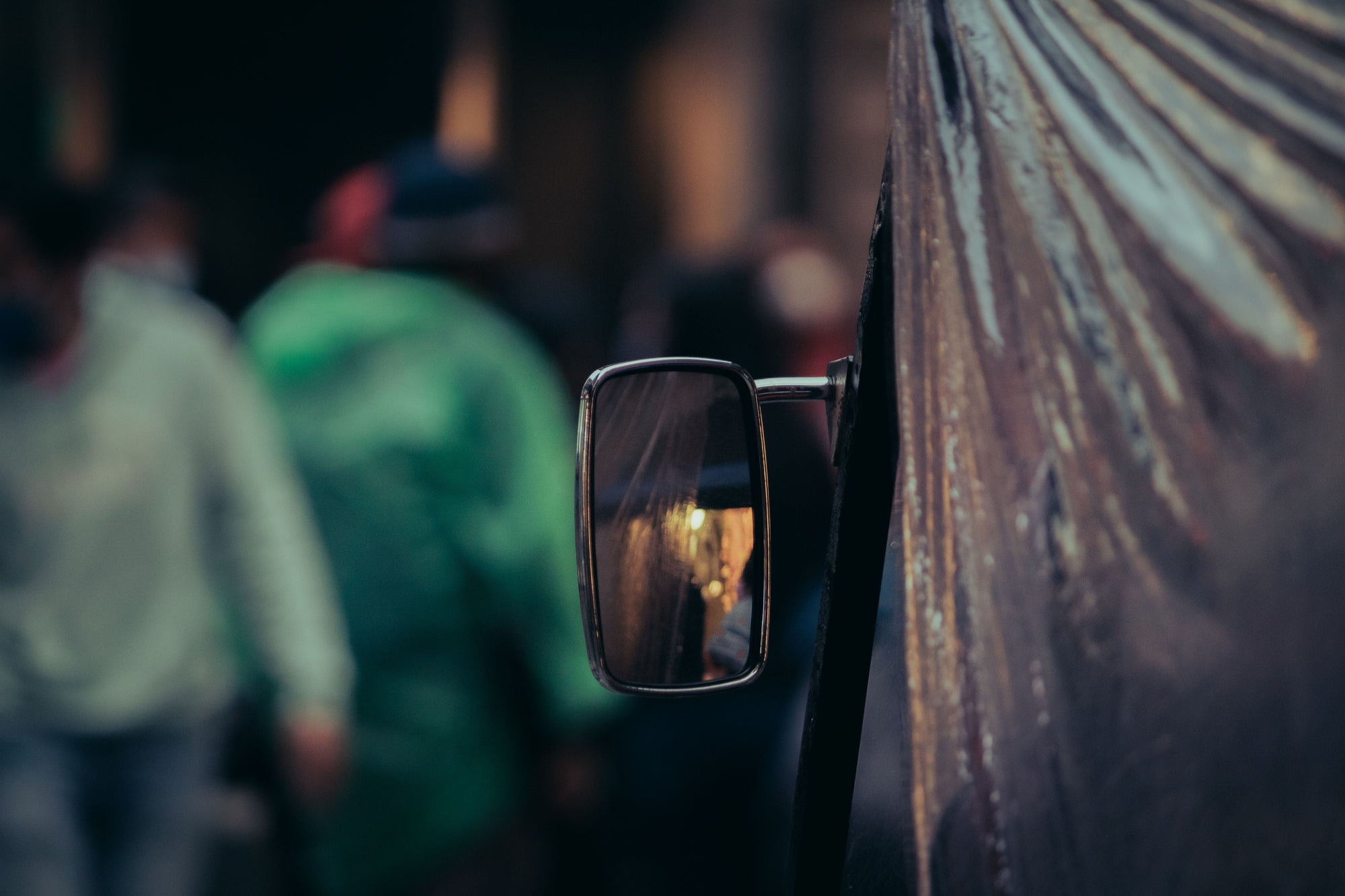 A close-up of a side mirror reflecting a blurred street scene.