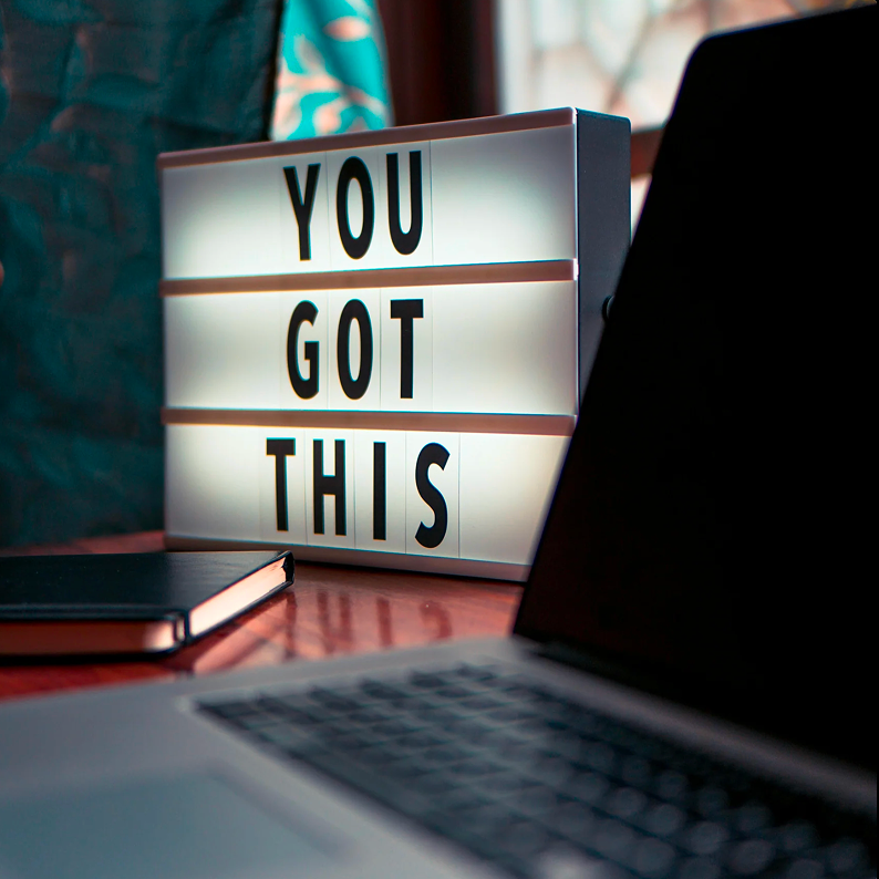 Lightbox with "YOU GOT THIS" message in front of a laptop on a desk.